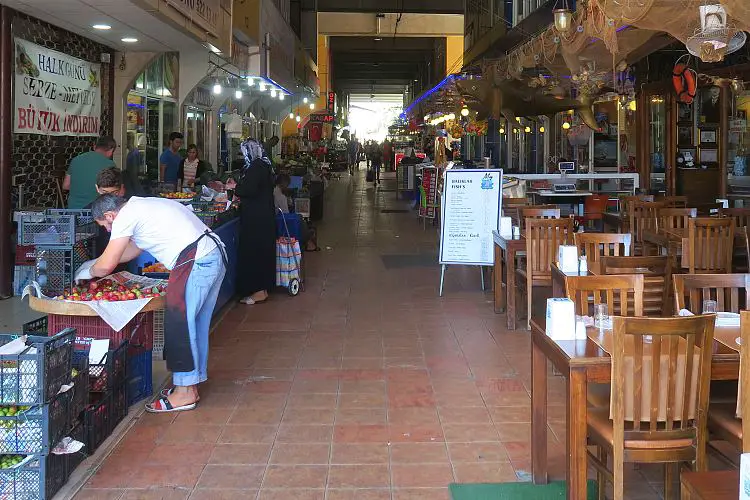 Das Innere der Fisch- und Markthalle mit Geschäften und Restaurants mit Sitzplätzen. Die Halle ist überdacht.