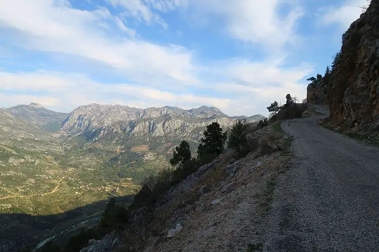 Eine Bergstraße mit einem weiten Ausblick auf das darunterliegende Tal. 