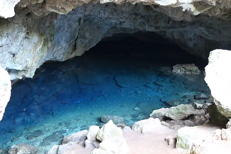 Eine Höhle mit kristallklaren türkisblauen Wasser. 