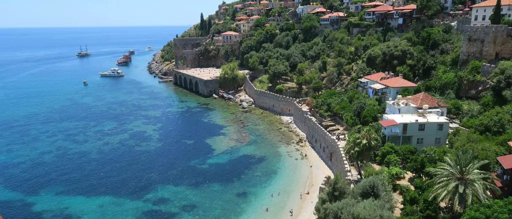 Hotels am schmalen Strand an den Hafenmauern von Alanya und dem türkisblauen Meer.