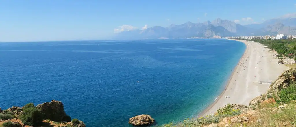 Das Wetter am Konyaaltistrand in Antalya im Mai ist sonnig und warm, Menschen schwimmen im türkisblauen Meer.