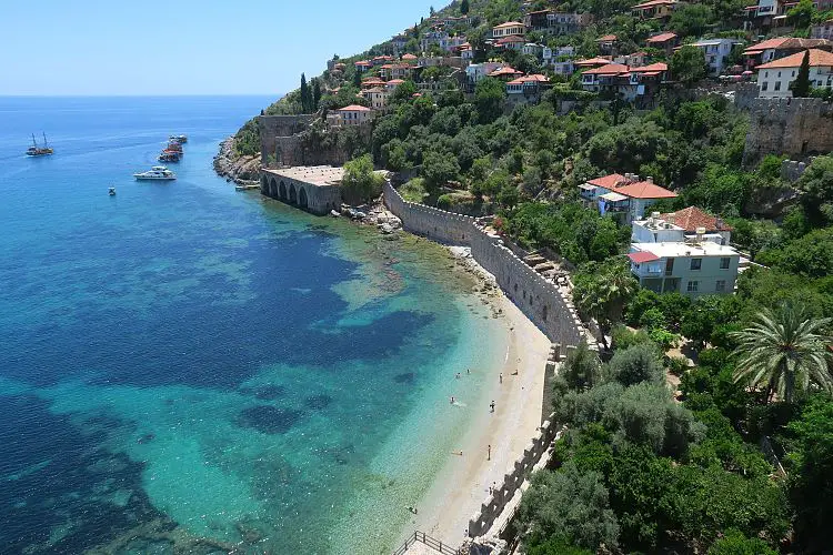 Türkisblaues Meer, die Hafenmauern, der Burgberg und das sonnige Wetter im Juni in Alanya. 