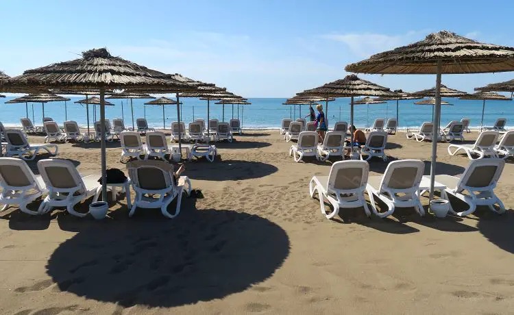 Sonnenliegen und Sonnenschirme am Sandstrand mit Blick auf das Meer