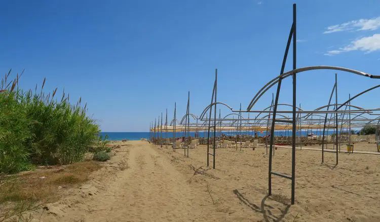 Sandstrand, Meer, ein Weg und Liegestühle im Hintergrund