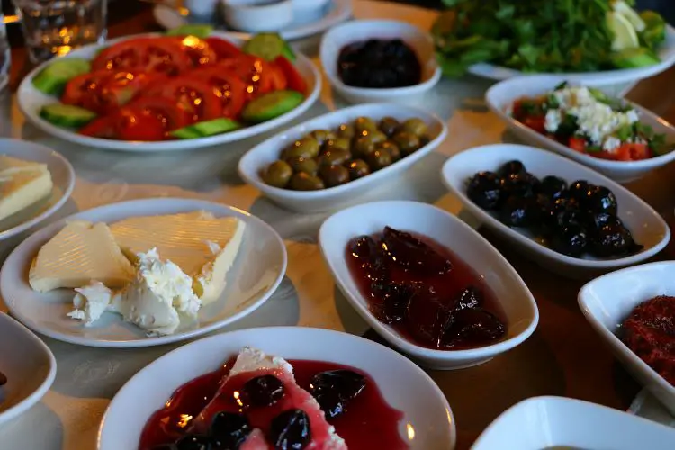Teller und Schalten mit den einzelnen Zutaten eins türkischen Frühstücks. Tomaten, Käse, Gurken, Marmelade, Oliven