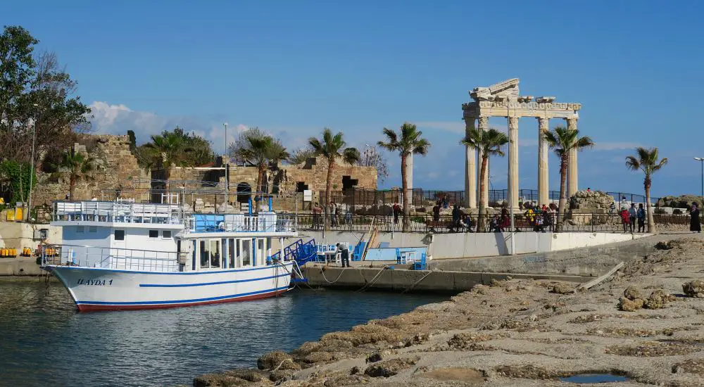 Ausflugsschiff im Hafen von Side mit dem Apollon Tempel im Hintergrund