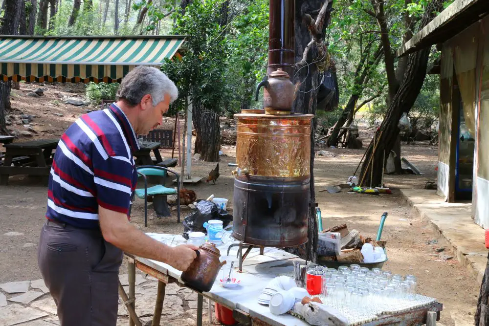 Ein Mann macht in einem Teegarten mit einem Samowar türkischen Tee