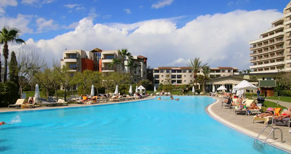 Türkisblauer Pool und das Haupthaus des Hotels.