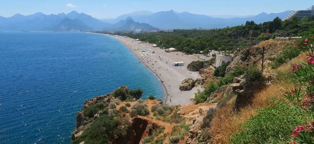 Kilometerlanger Strand mit Antalya und Bergen im Hintergrund