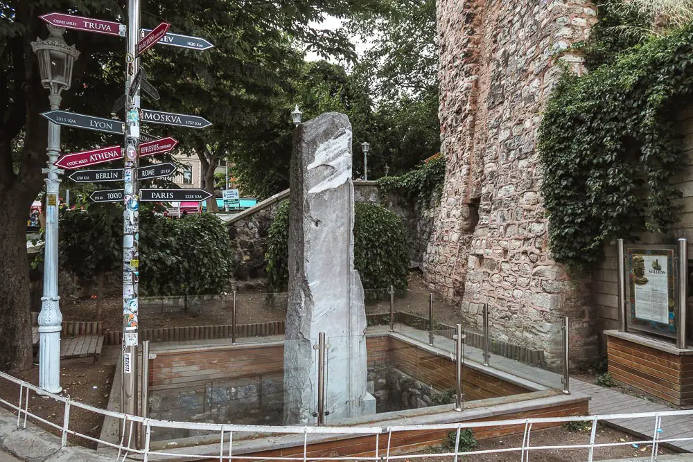 Der Millenium Stein steht von einem Zaun umgeben unter einem Baum