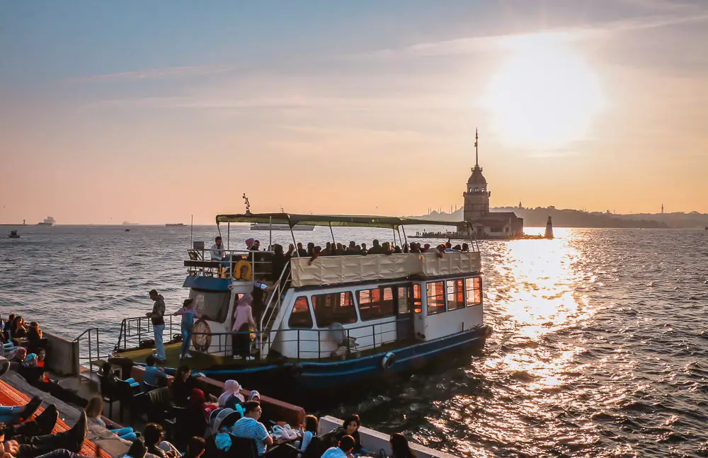 Boot am Bosporusufer mit dem Mädchenturm und der untergehenden Sonne im Hintergrund