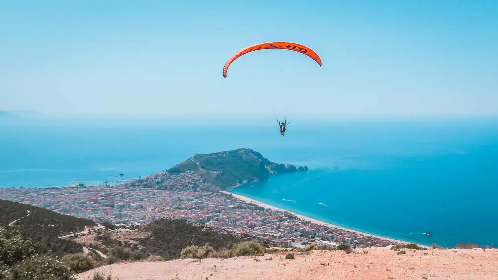 Paraglider der gerade von einem Gipfel im Taurusgebirge losgeflogen ist in Richtung des Kleopatrastrand