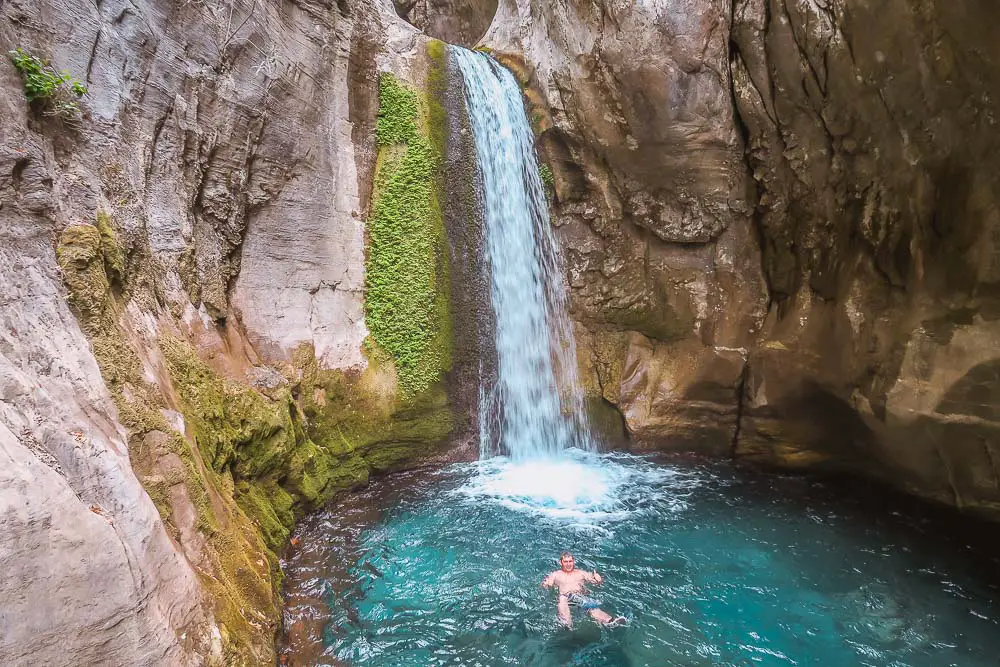 Ein Mann schwimmt unter einem Wasserfall im Sapadere Canyon