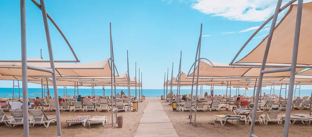 Sonnenliegen und Sonnenschirme am Strand von Konakli mit Blick auf das Meer der türkischen Riviera