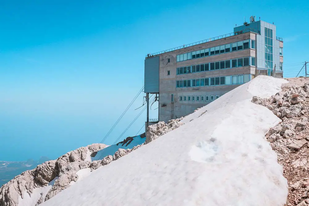 Bergstation der Olympos Seilbahn mit Ausblick auf die Küste und Schnee auf dem Berg