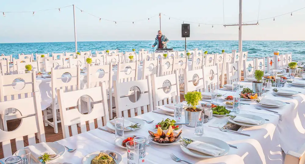 Weiße Tisch und Stühle, Essen, ein Dj und das Meer im Hintergrund