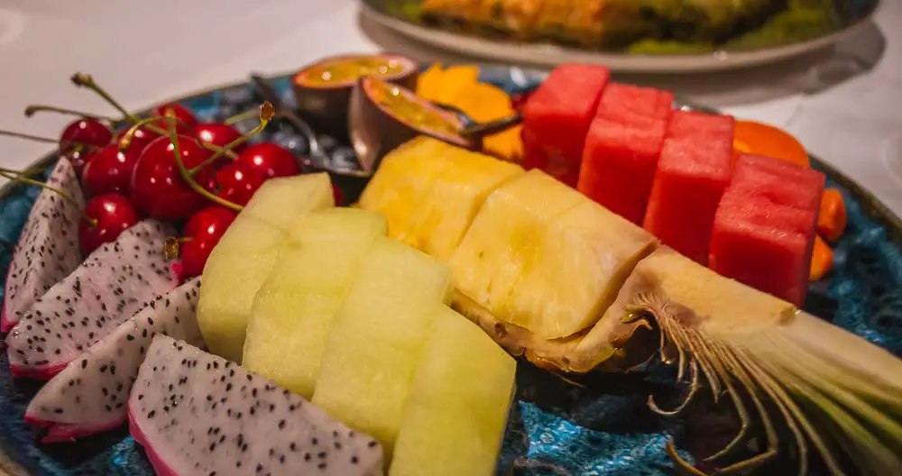 Mango, Drachenfrucht, Melonen, Honigmelonen, Feigen und Kirchen liegen auf einem Teller