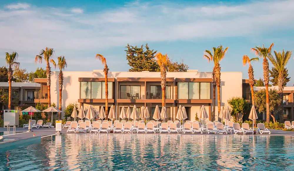 Hotelzimmer am Pool mit Sonnenliegen, Sonnenschirmen und Palmen